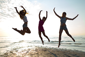 Image showing happy female friends dancing and jumping on beach