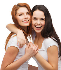 Image showing two laughing girls in white t-shirts hugging