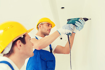 Image showing group of builders with drill indoors