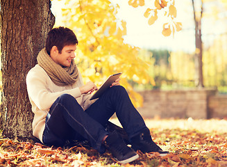 Image showing smiling young man with tablet pc in autumn park