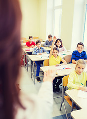 Image showing group of school kids raising hands in classroom