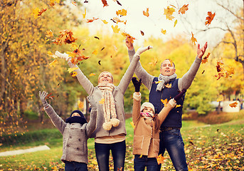 Image showing happy family playing with autumn leaves in park