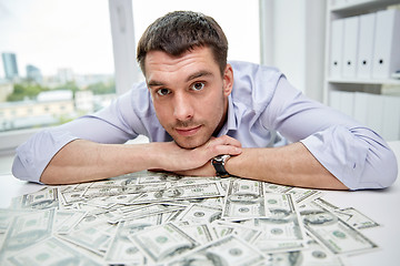 Image showing happy businessman with heap of money in office