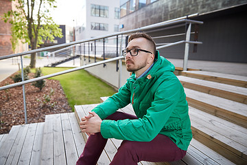 Image showing happy young hipster man sitting on stairs in city