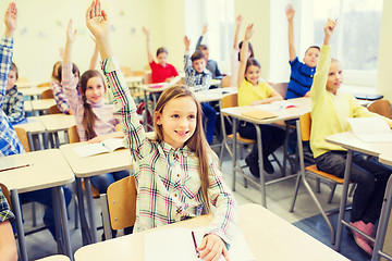 Image showing group of school kids raising hands in classroom