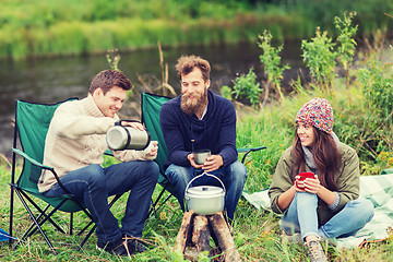 Image showing group of smiling tourists cooking food in camping