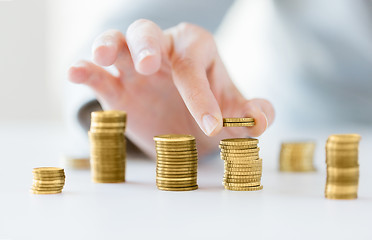 Image showing close up of female hand putting coins into columns