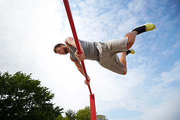 Image showing young man exercising on horizontal bar outdoors