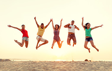 Image showing smiling friends dancing and jumping on beach