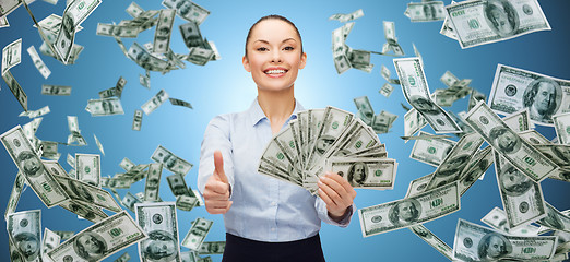 Image showing smiling businesswoman with money showing thumbs up