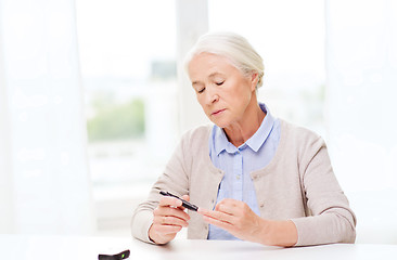 Image showing senior woman with glucometer checking blood sugar