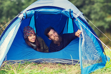 Image showing smiling couple of tourists looking out from tent