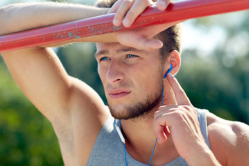 Image showing young man with earphones and horizontal bar