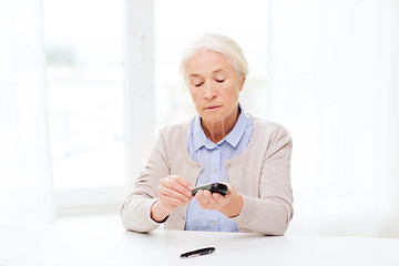 Image showing senior woman with glucometer checking blood sugar