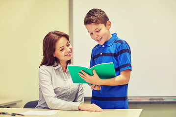 Image showing school boy with notebook and teacher in classroom