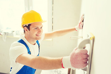 Image showing smiling builder with grinding tool indoors