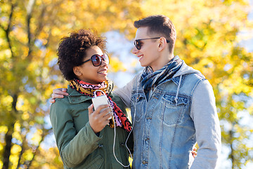 Image showing smiling couple with smartphone and earphones