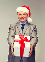 Image showing smiling man in suit and santa helper hat with gift