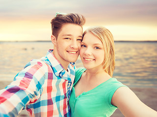 Image showing smiling couple with smartphone on summer beach