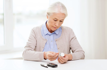 Image showing senior woman with glucometer checking blood sugar