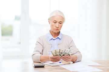 Image showing senior woman with money and papers at home