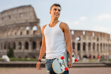 Image showing smiling teenage boy with skateboard over coliseum