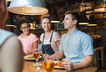 Image showing happy friends eating and drinking at bar or pub