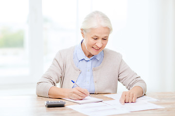 Image showing senior woman with papers and calculator at home