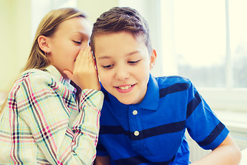 Image showing smiling schoolgirl whispering to classmate ear