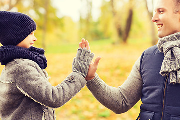 Image showing happy father and son making high five in park