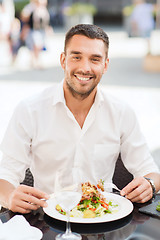 Image showing happy man eating salad for dinner at restaurant