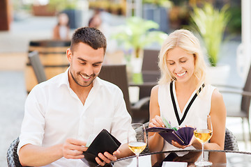 Image showing happy couple with wallet paying bill at restaurant