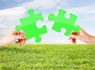 Image showing hands with green puzzle over natural background