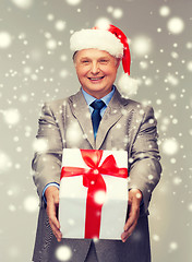 Image showing smiling man in suit and santa helper hat with gift