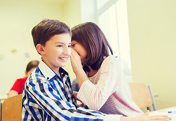 Image showing smiling schoolgirl whispering to classmate ear