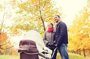 Image showing smiling couple with baby pram in autumn park