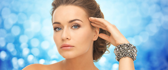 Image showing beautiful woman with bracelets over blue lights