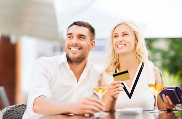 Image showing happy couple with bank card and bill at restaurant