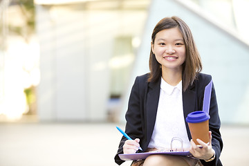 Image showing Young female Asian business executive holding file