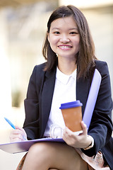 Image showing Young female Asian business executive holding file