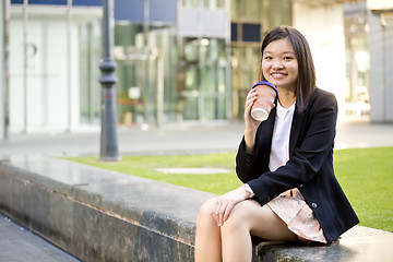 Image showing Young female Asian executive drinking coffee