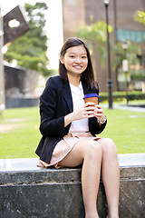 Image showing Young female Asian executive drinking coffee