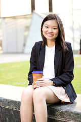 Image showing Young female Asian executive drinking coffee