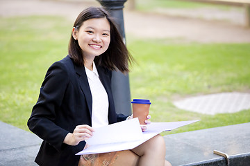 Image showing Young female Asian business executive holding file