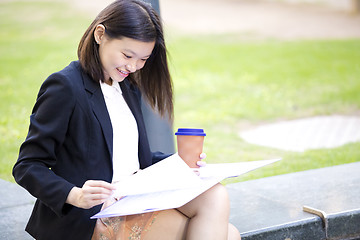 Image showing Young female Asian business executive holding file