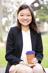 Image showing Young female Asian executive drinking coffee