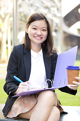 Image showing Young female Asian business executive holding file