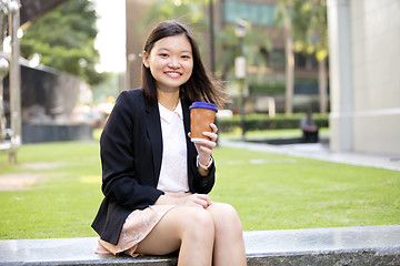 Image showing Young female Asian executive drinking coffee