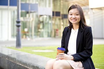 Image showing Young female Asian executive drinking coffee