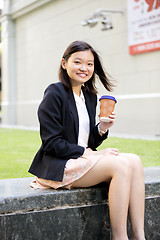 Image showing Young female Asian executive drinking coffee